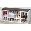 Weißer Schuhschrank mit braunem Sitzkissen und mehreren Paar Schuhen.