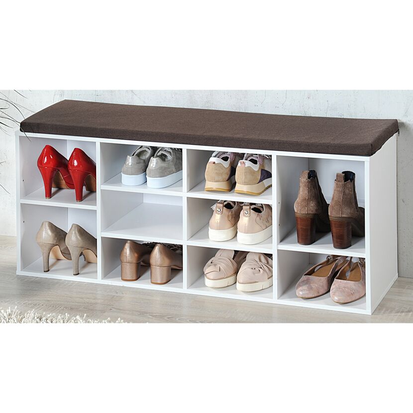 Weißer Schuhschrank mit braunem Sitzkissen und mehreren Paar Schuhen.