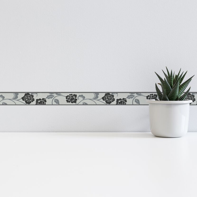 Schwarze Blumenborte an weißer Wand.