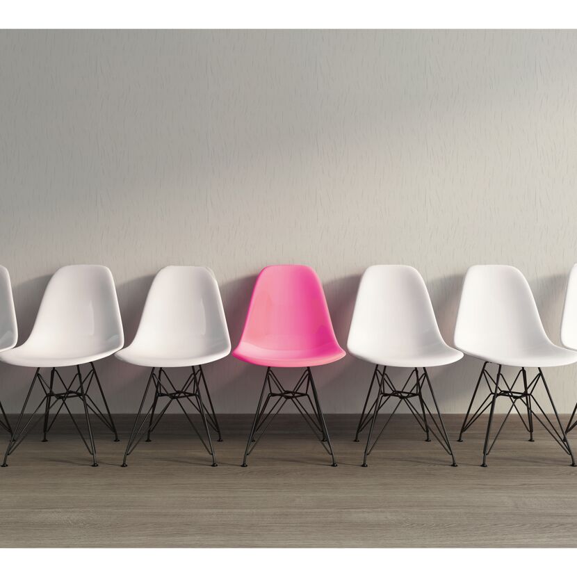 Reihe weißer Stühle mit einem pinken Stuhl in der Mitte.