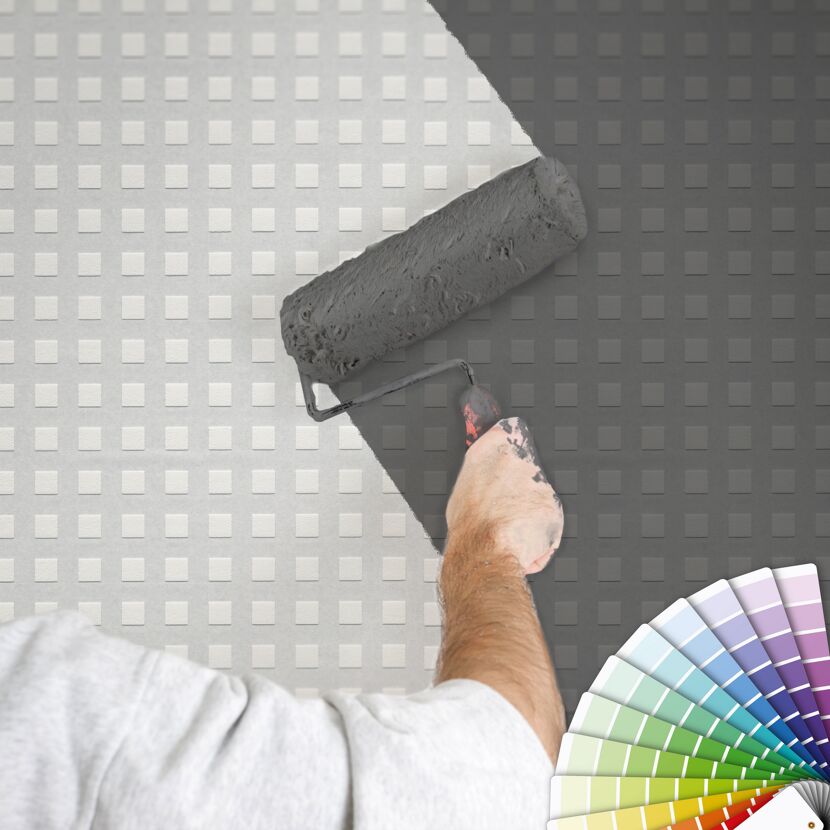 Person streicht weiße Wand mit grauer Farbe