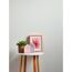 Beistelltisch mit Pflanze, Deko-Häusern und gerahmtem Bild