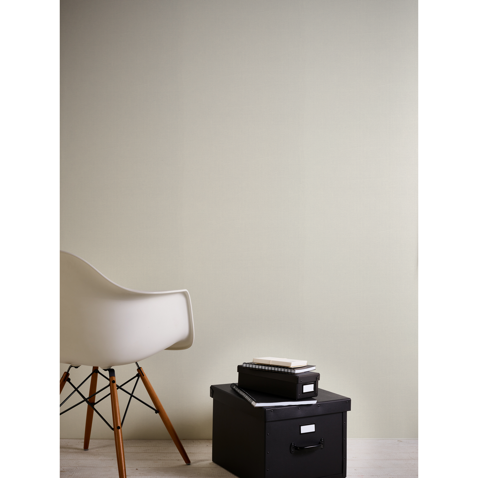 Weißer Stuhl und schwarze Boxen vor beiger Wand
