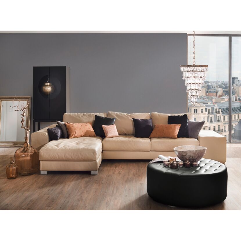 Beiges Ledersofa mit Kissen und schwarzem Hocker