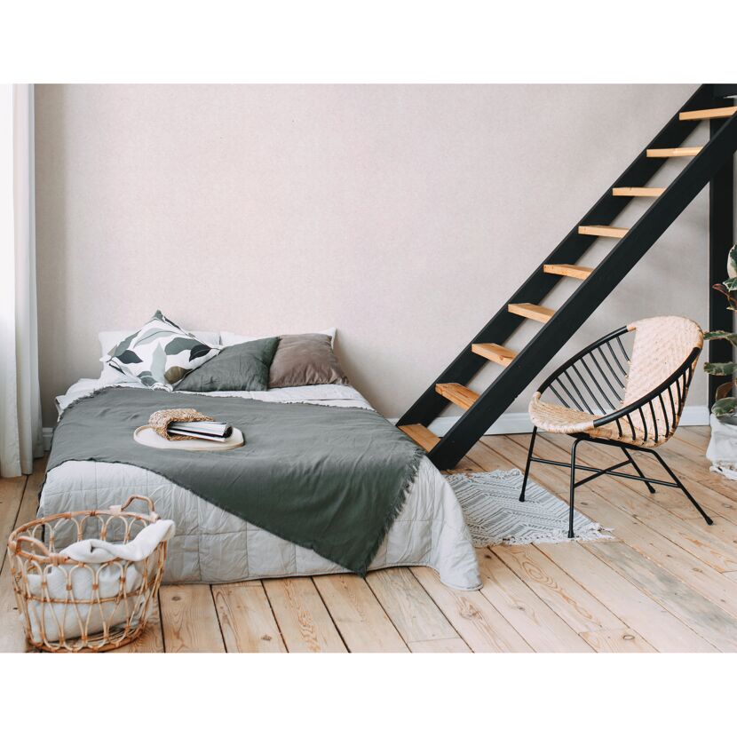 Schlafzimmer mit Bett, Korbstuhl und Treppe