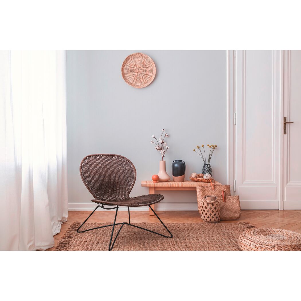 Wohnzimmer mit geflochtenem Stuhl und Deko-Artikeln