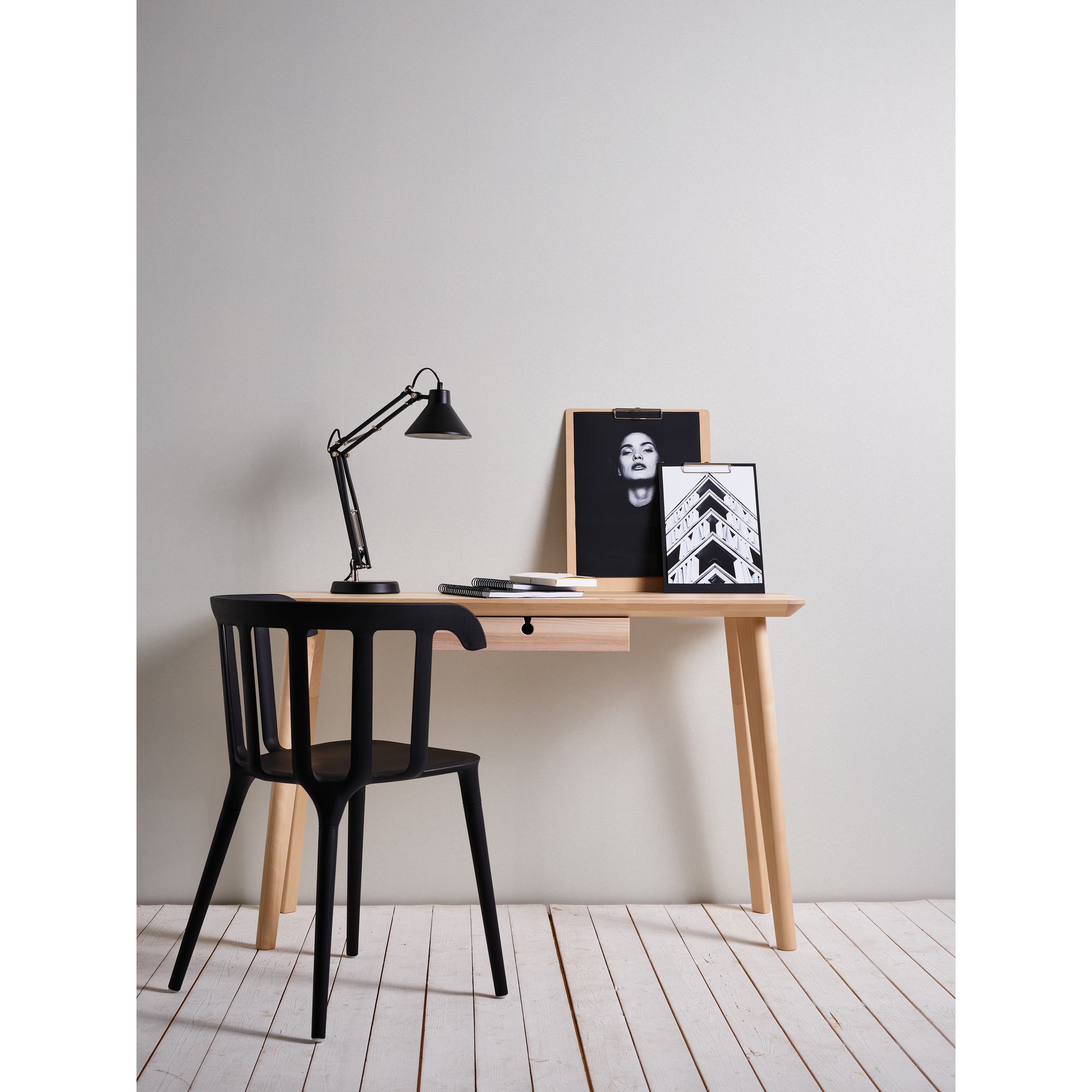Schreibtisch mit Lampe, schwarzem Stuhl und Bildern