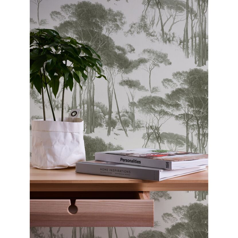 Zimmerecke mit beiger Kommode, Pflanze und Büchern vor einer Fototapete mit Waldmotiv.