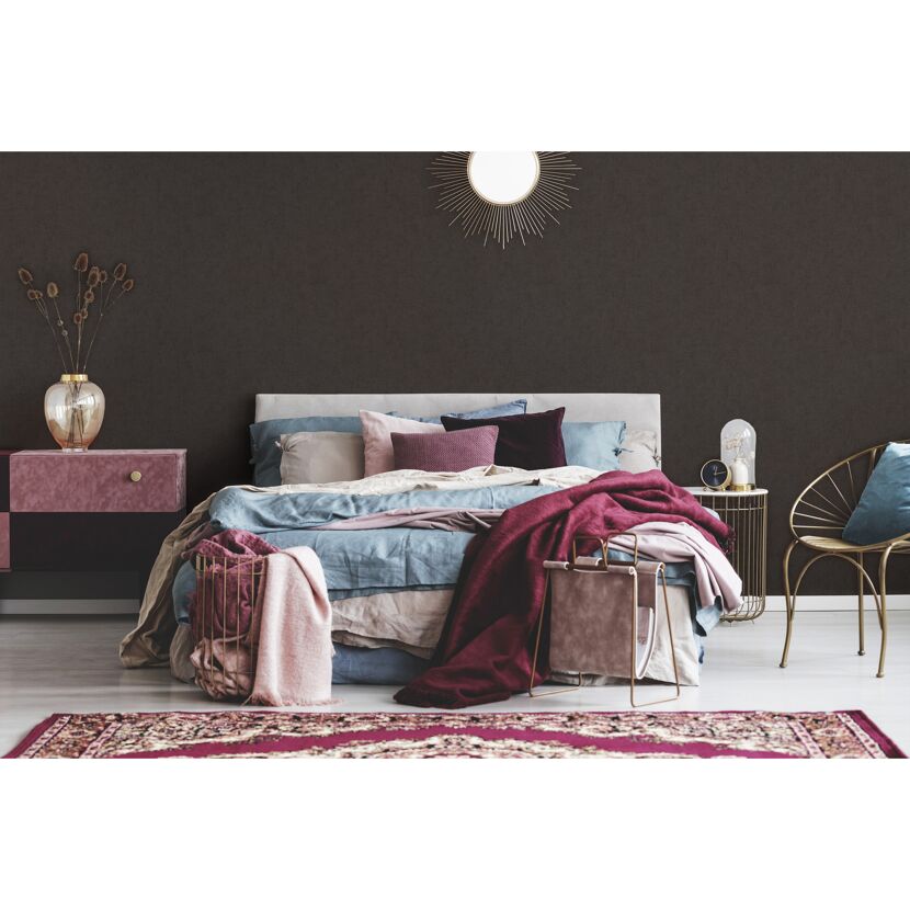 Schlafzimmer mit dunkler Wand und Bett mit bunten Decken