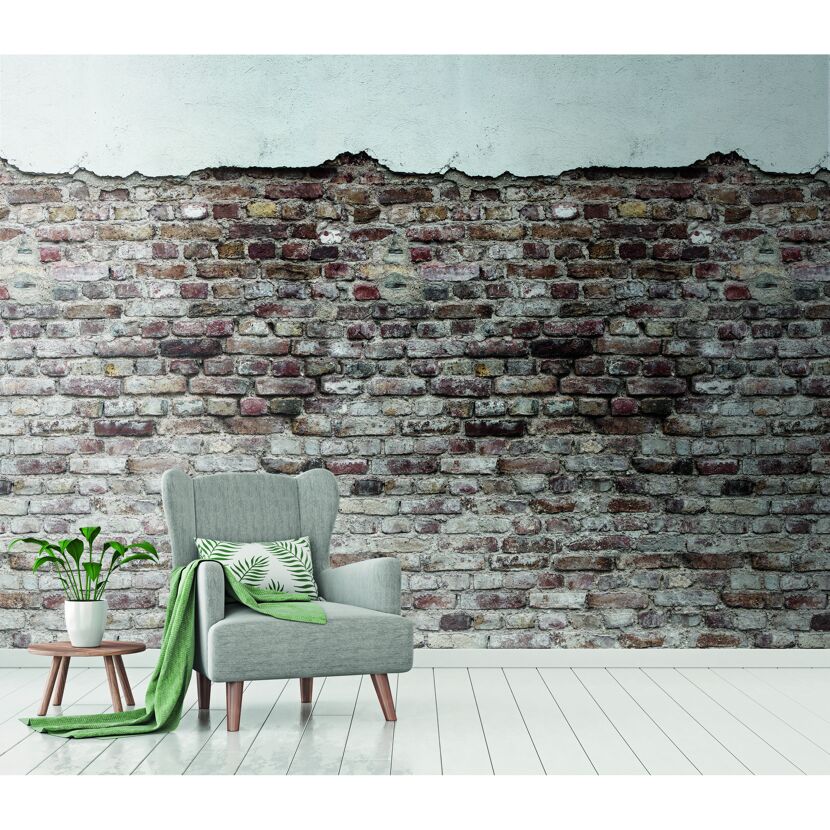 Sessel mit grüner Decke und Pflanze vor Backsteinwand
