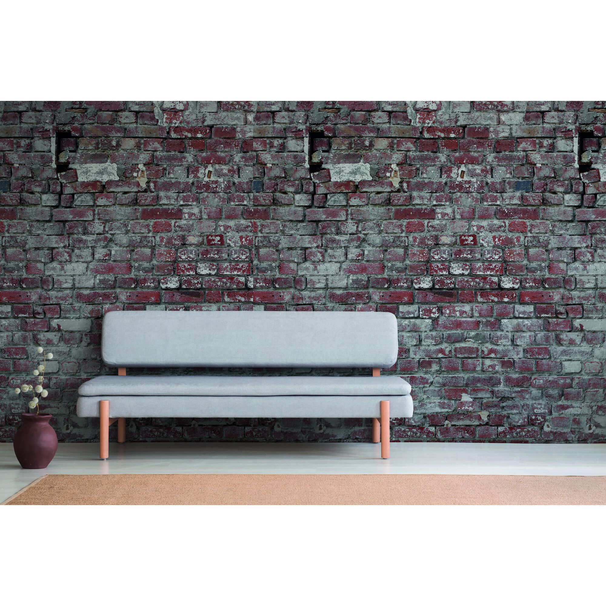 Graues Sofa vor Backsteinwand