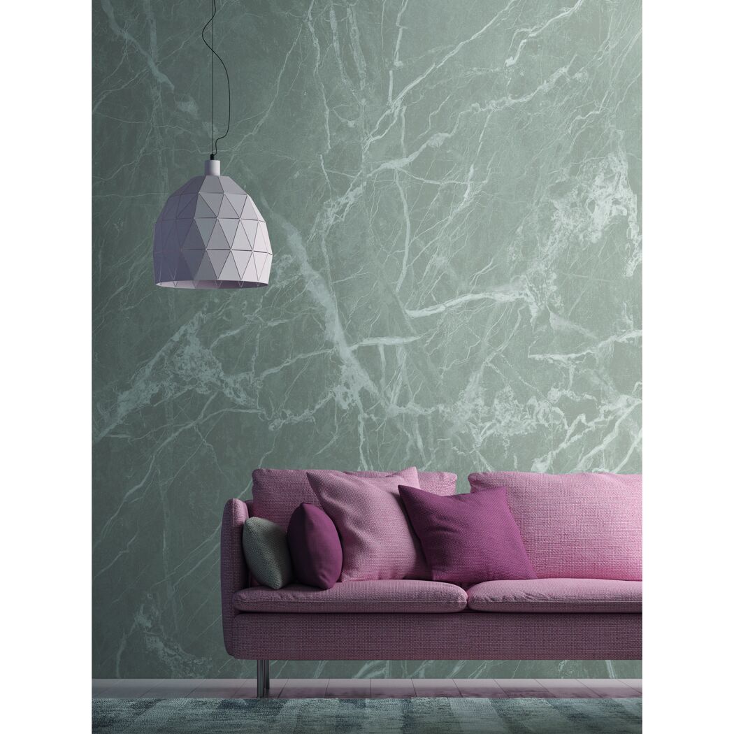 Rosa Sofa vor grün marmorierter Wand, darüber eine Lampe.