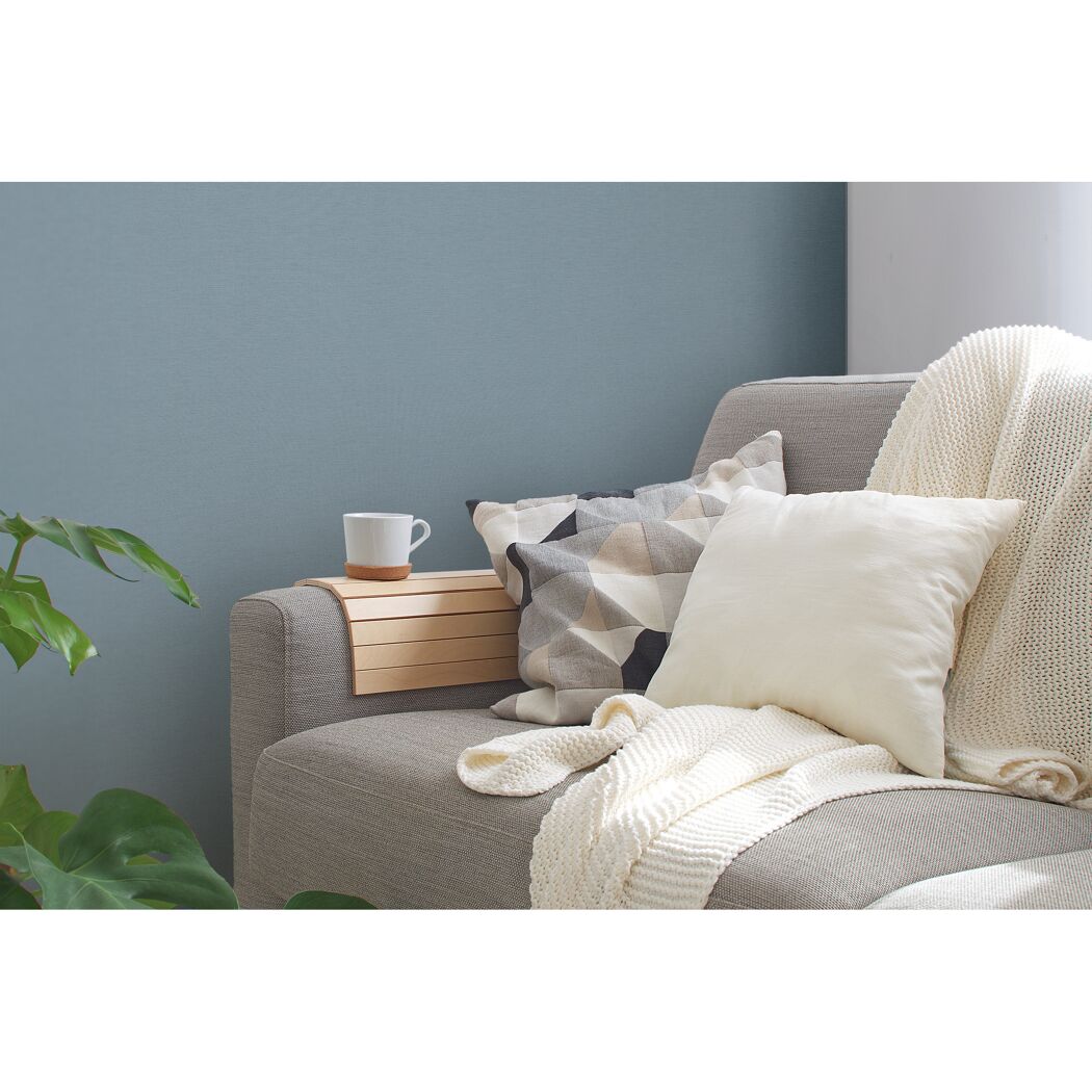 Sofa mit Kissen, Decke und einem kleinem Tisch mit Tasse