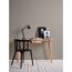 Arbeitsplatz mit Schreibtisch, Lampe und Bildern vor grauer Wand.