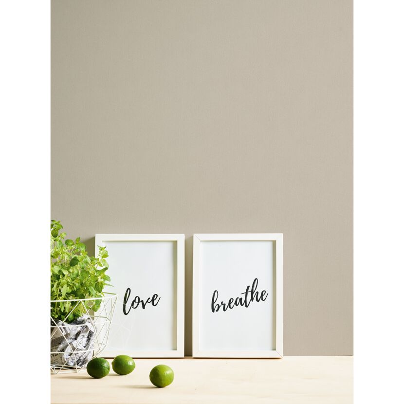 Zwei gerahmte Kunstdrucke mit den Aufschriften "love" und "breathe", daneben Limetten und eine Pflanze.
