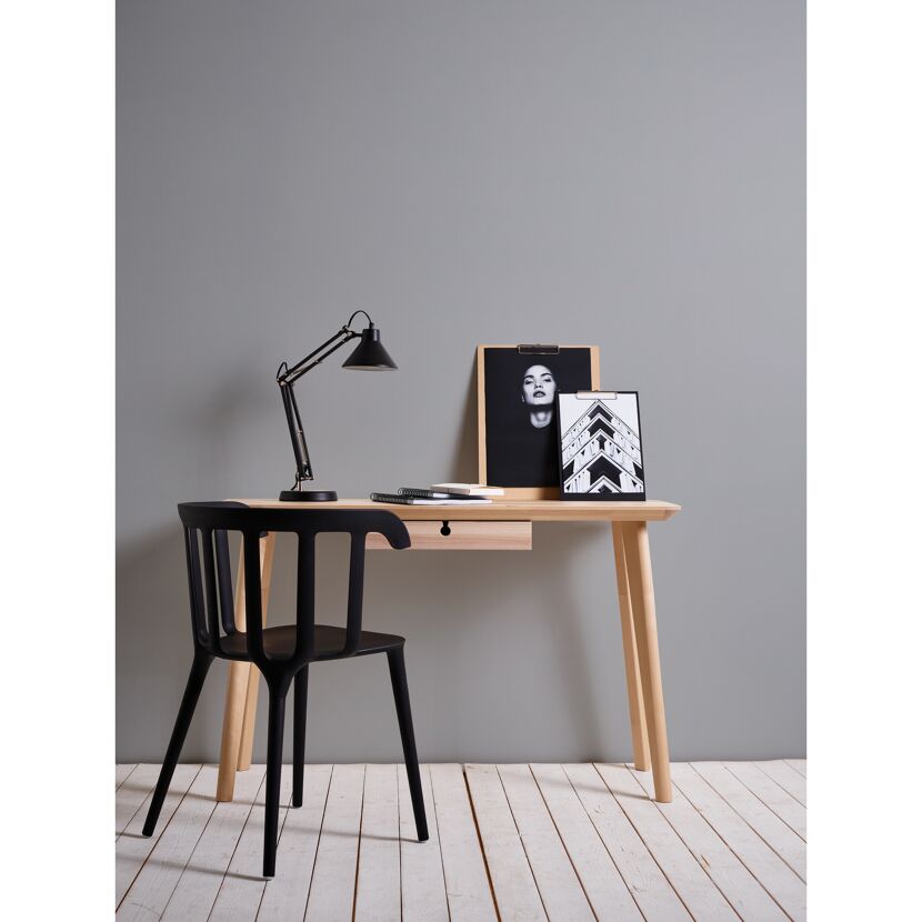 Schreibtisch mit Lampe, Bildern und schwarzem Stuhl