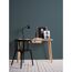 Schreibtisch mit Lampe und Bildern vor petrolfarbener Wand