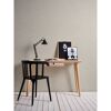 Schreibtisch mit Lampe und Bildern vor beiger Wand