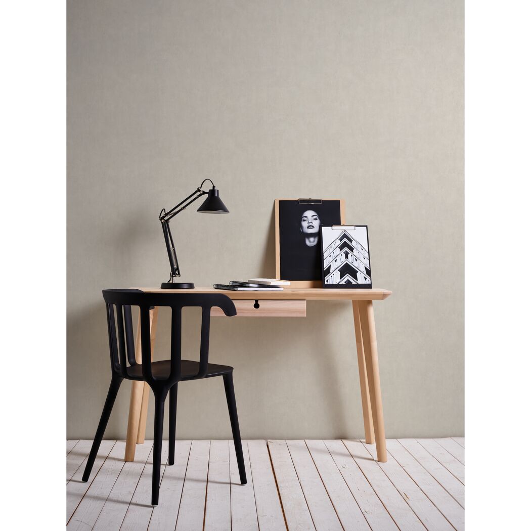 Schreibtisch mit Lampe und Bildern vor beiger Wand