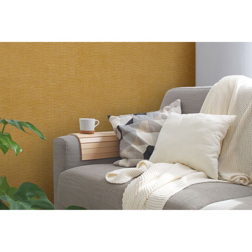 Wohnzimmer mit senffarbener Vliestapete und grauer Couch