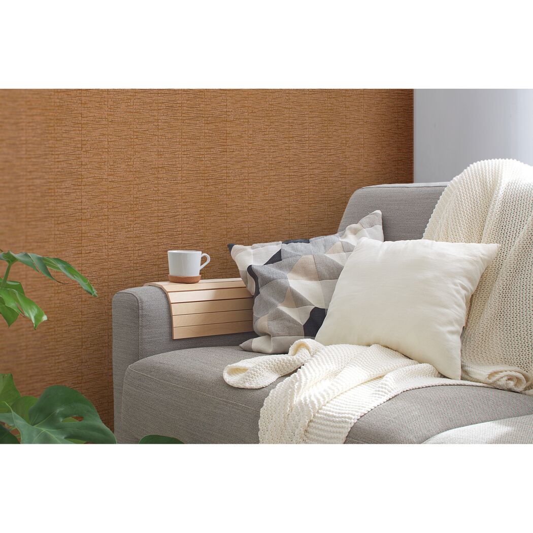 Sofa mit Kissen und Decke vor brauner Wand