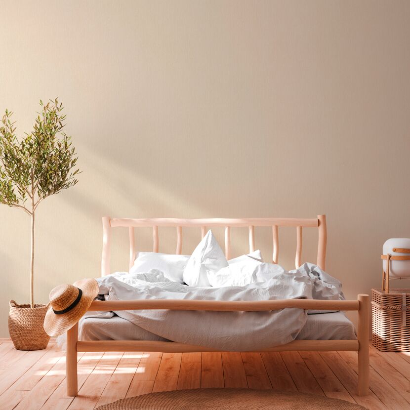 Schlafzimmer mit Bett, Pflanze und Korbmöbeln