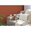 Sofa mit Kissen und Decke vor rotbrauner Wand