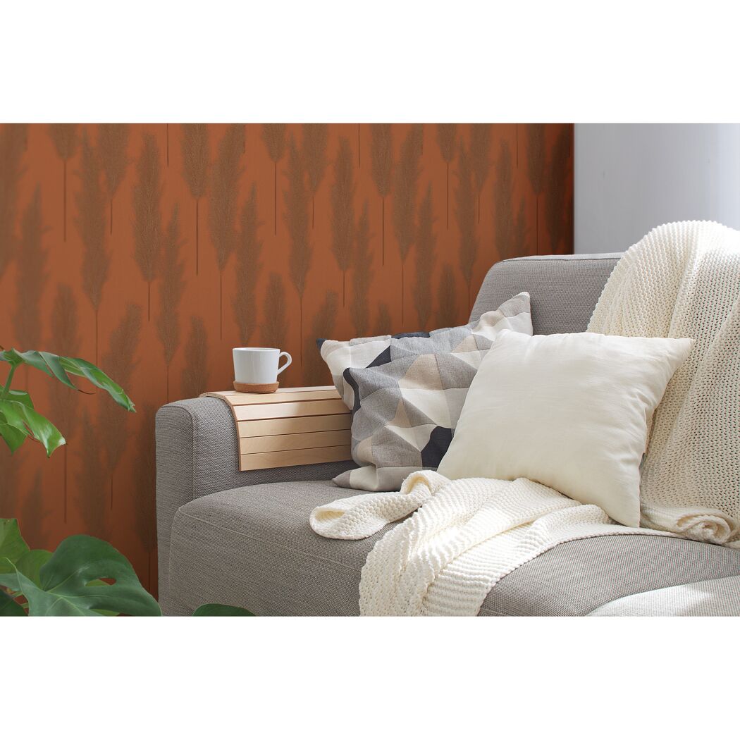 Sofa mit Kissen und Decke vor einer mit Pampasgras gemusterten Wand