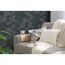 Sofa mit Kissen und Decke vor grauer Wabenwand.
