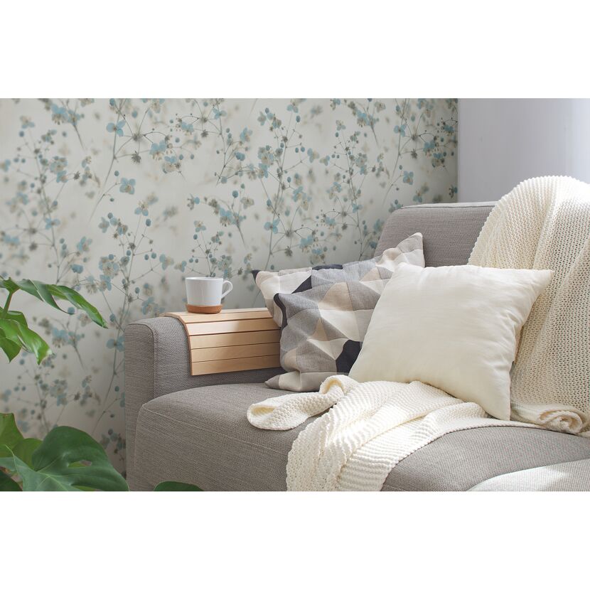 Gemütliches Wohnzimmer mit Blumentapete und beiger Couch