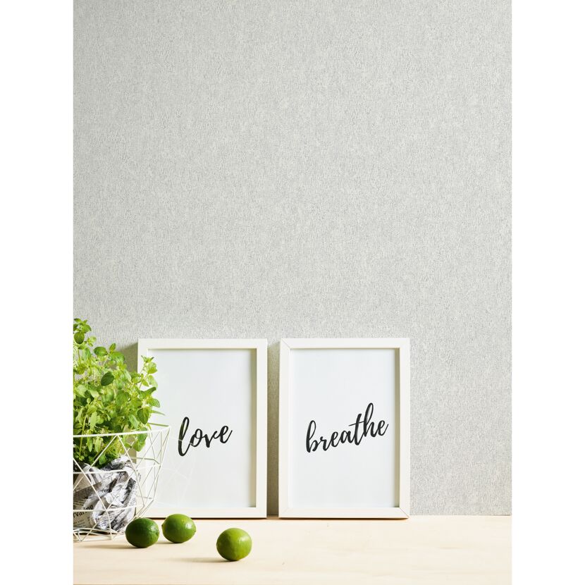 Zwei Bilderrahmen mit den Worten Liebe und Atmen. Daneben steht eine Pflanze und Limetten.