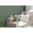 Sofa mit Kissen und Decke vor dunkelgrüner Wand