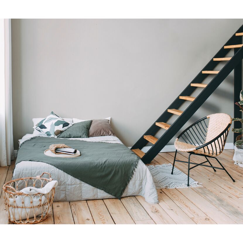 Schlafzimmer mit Bett, Korbstuhl und Holztreppe