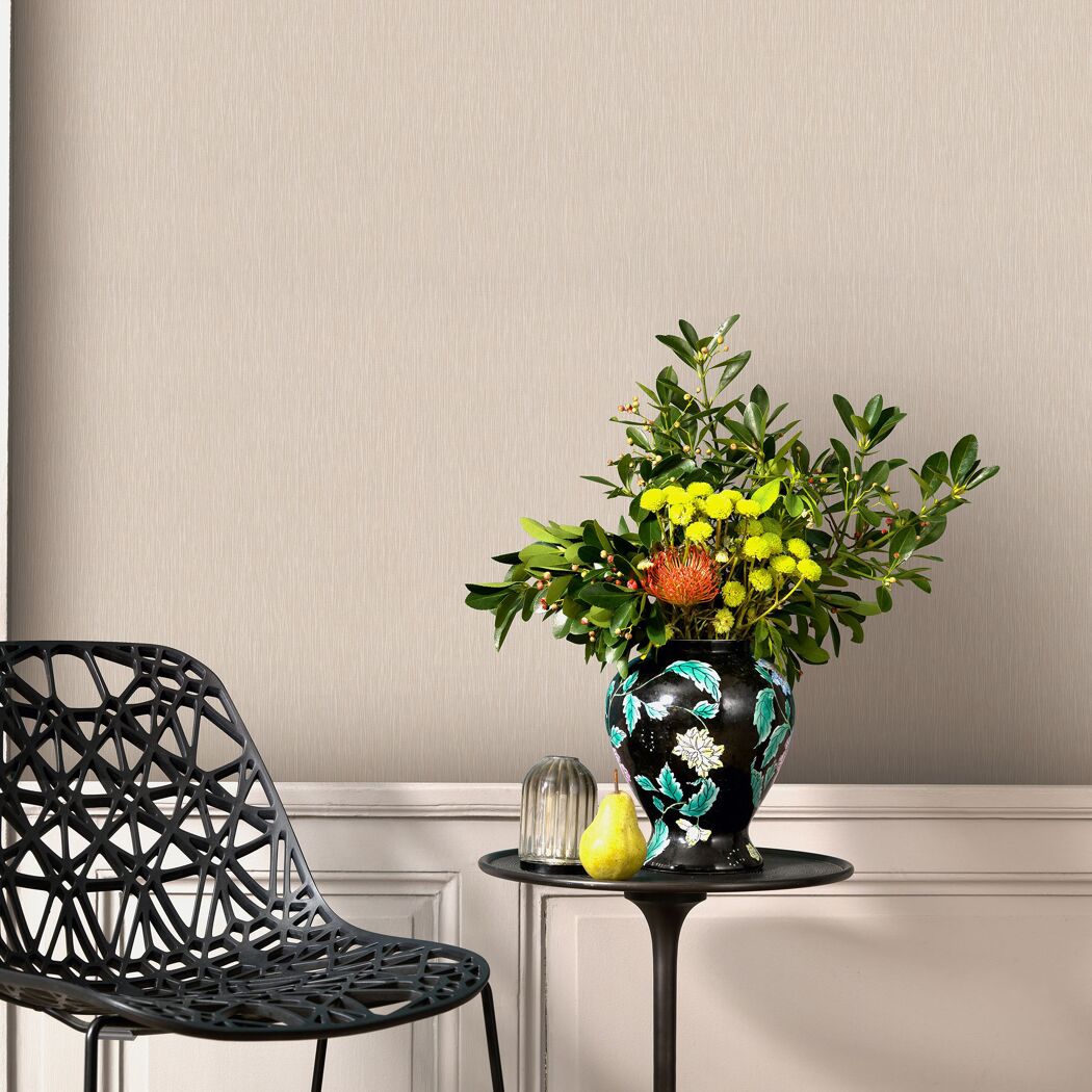 Beige Vliestapete an der Wand. Blumenstrauß und ein moderner Stuhl