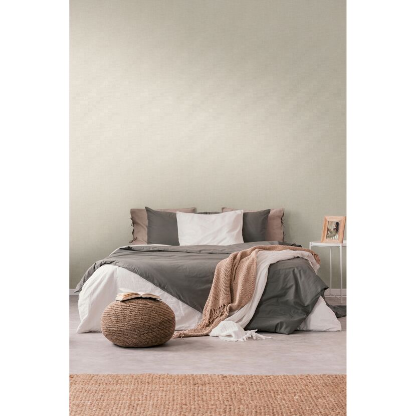 Gemachtes Bett mit beigefarbener Tapete