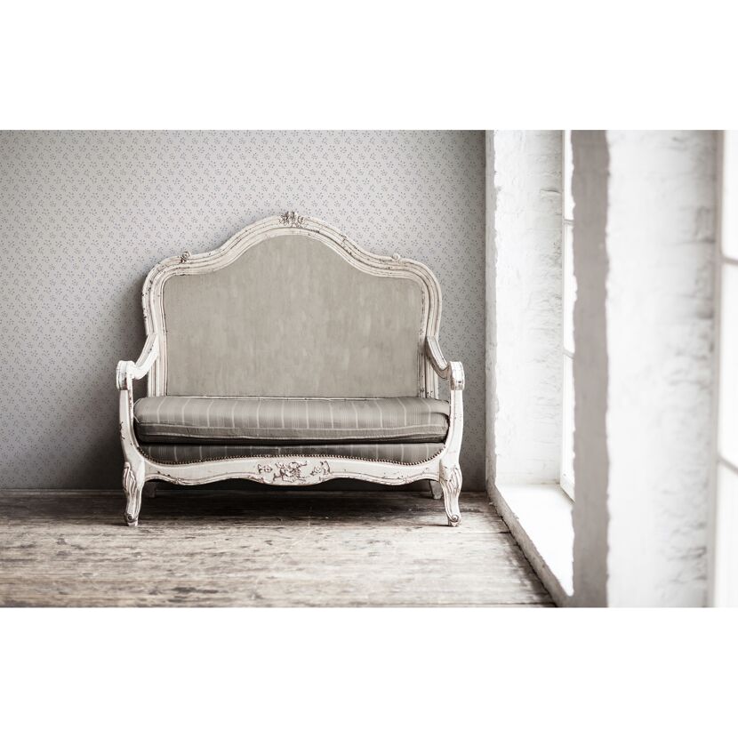 Alter weißer Sofa vor geblümter Wand