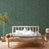 Bett mit Bettwäsche vor grün-goldener Tapete mit Blattmotiv