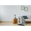 Holzhocker, Sofa und Bilderrahmen mit Pflanzenmotiv an einer Wand.
