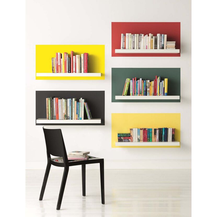 Bunte Wand mit Regalen und Büchern, ein Stuhl steht davor