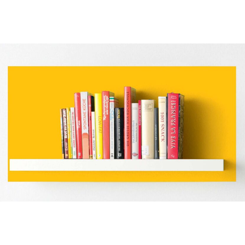 Bücherregal mit Kochbüchern vor gelber Wand