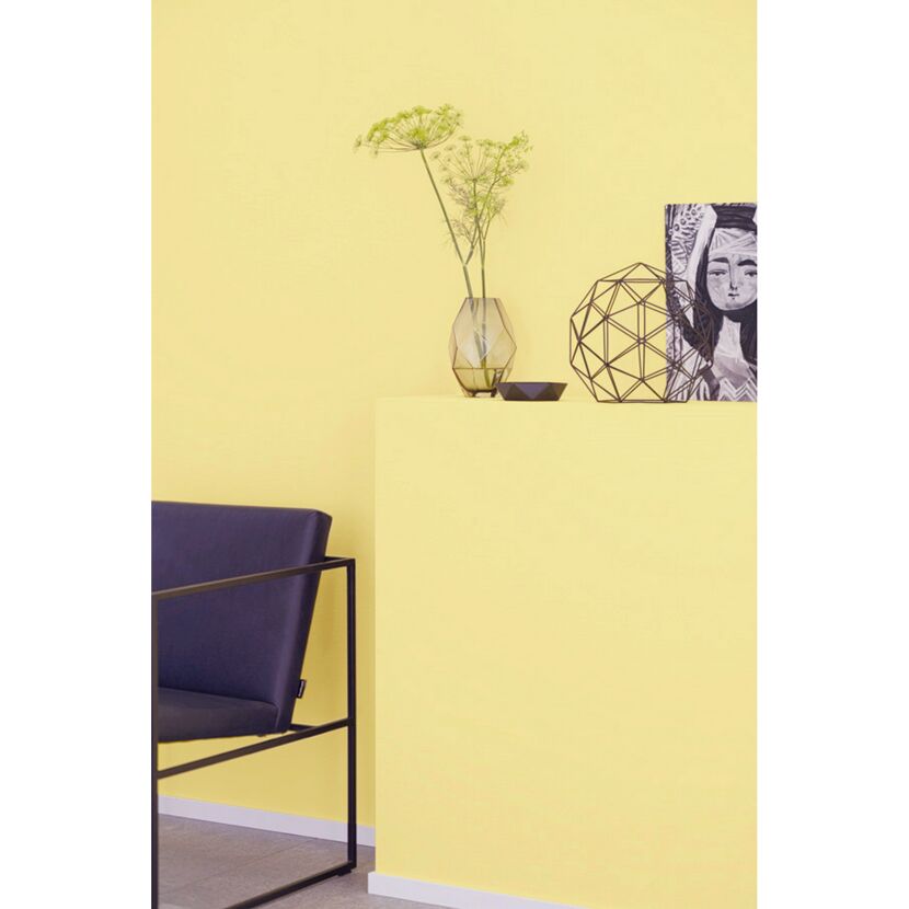 Gelbe Wand mit Deko und Sessel
