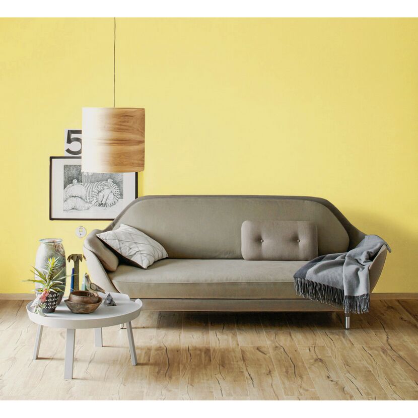 Wohnzimmer mit Sofa, gelber Wand und Hängelampe
