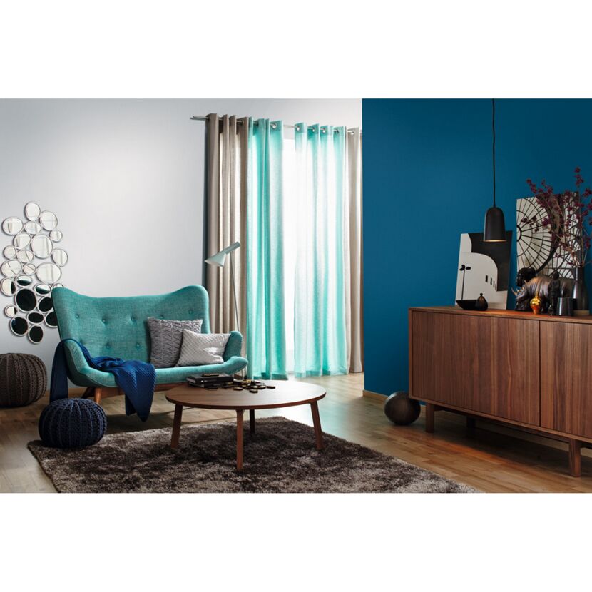 Wohnzimmer mit türkisfarbenem Sofa und blauer Wand