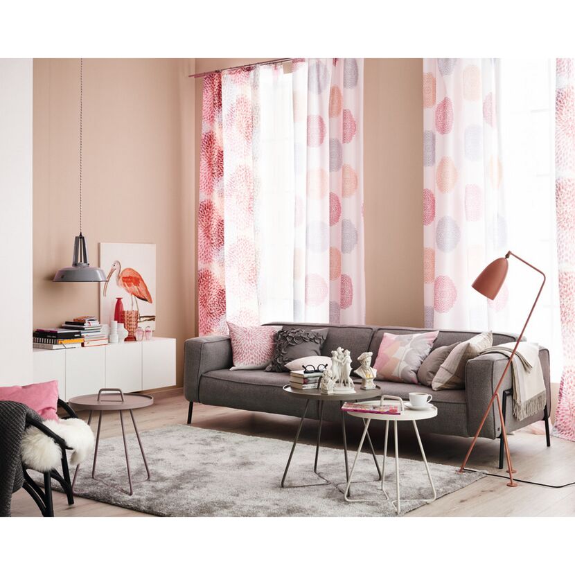 Wohnzimmer mit Sofa, Vorhängen und Deko in Rosa- und Rottönen