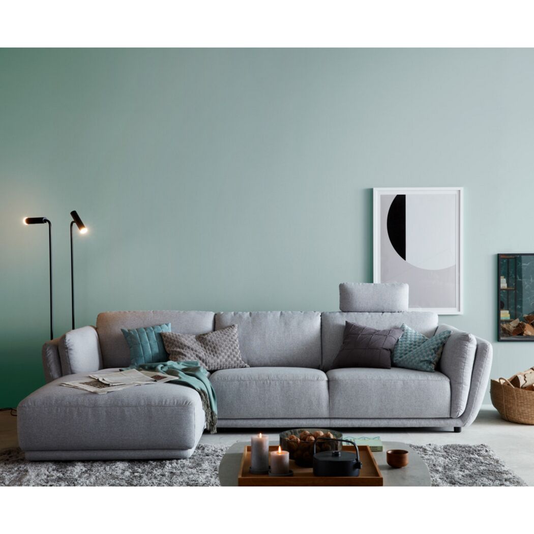 Gemütliches Wohnzimmer mit hellgrauem Sofa und türkisfarbener Wand