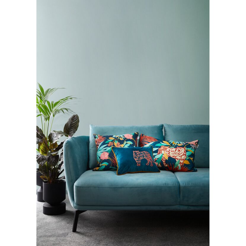 Türkisfarbenes Sofa mit gemusterten Kissen und Zimmerpflanze