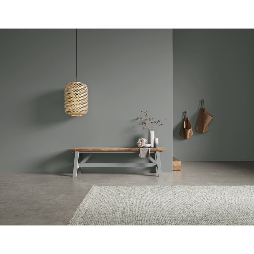 Holzbank mit Deko und Bambuslampe an grauer Wand.