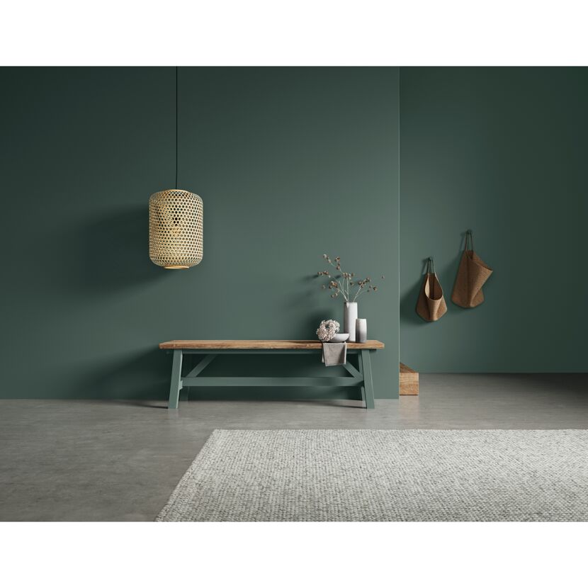 Holzbank mit Dekoelementen und Bambuslampe an dunkelgrüner Wand