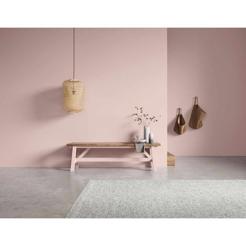 Rosa gestrichener Flur mit Holzbank und Korblampen.