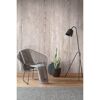Stuhl und Stehlampe vor Betonwand